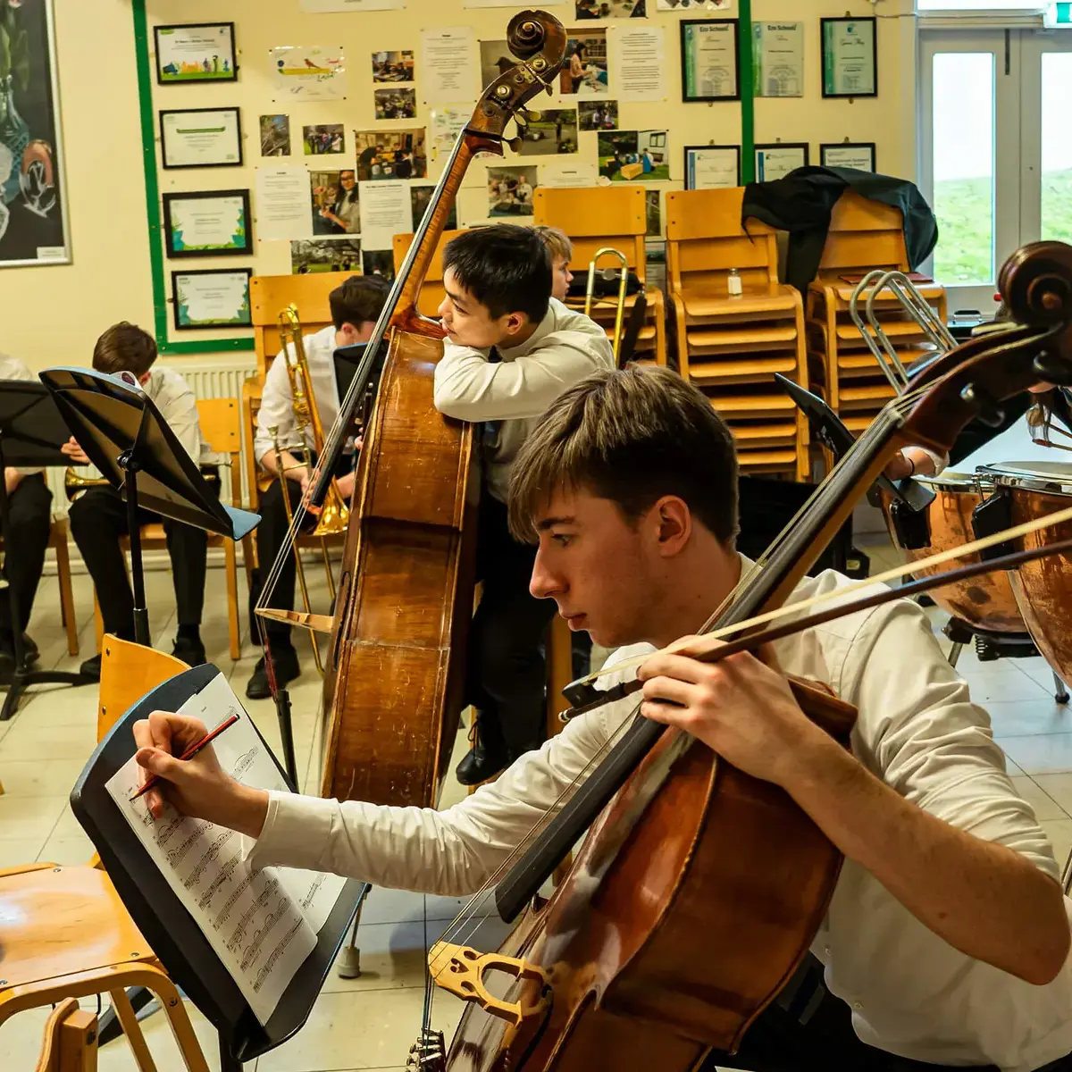 Pupils in an orchestral rehearsal making notes